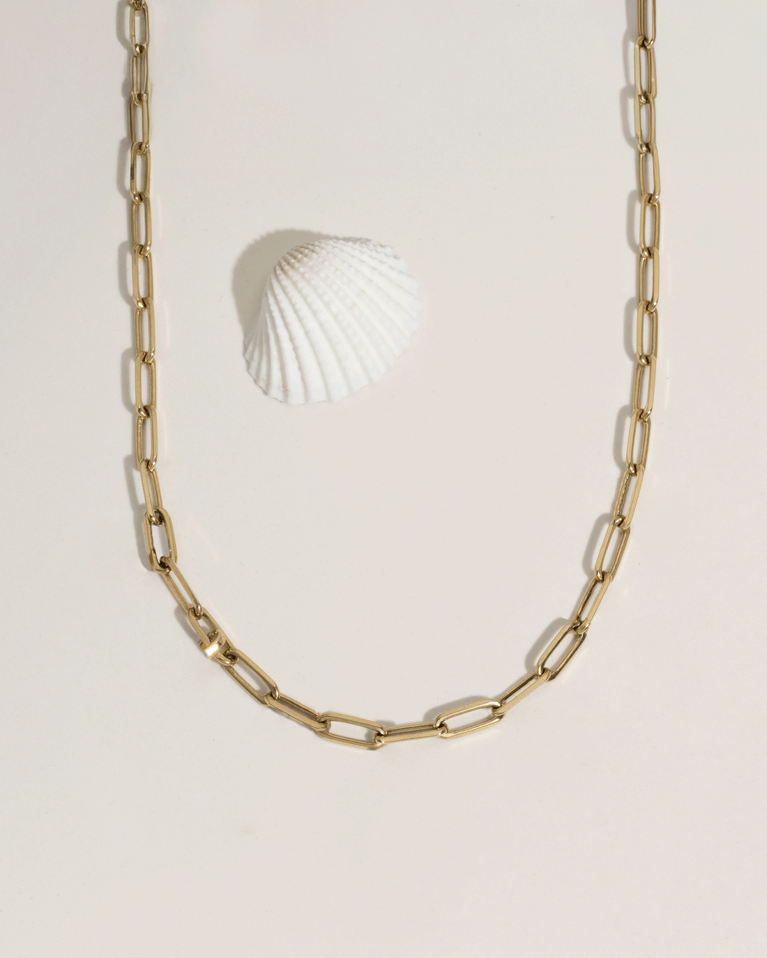Animated GIF showing model wrist with stacked gold bracelets under flowing water, water resistance demo
