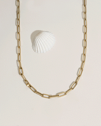Animated GIF showing model wrist with stacked gold bracelets under flowing water, water resistance demo