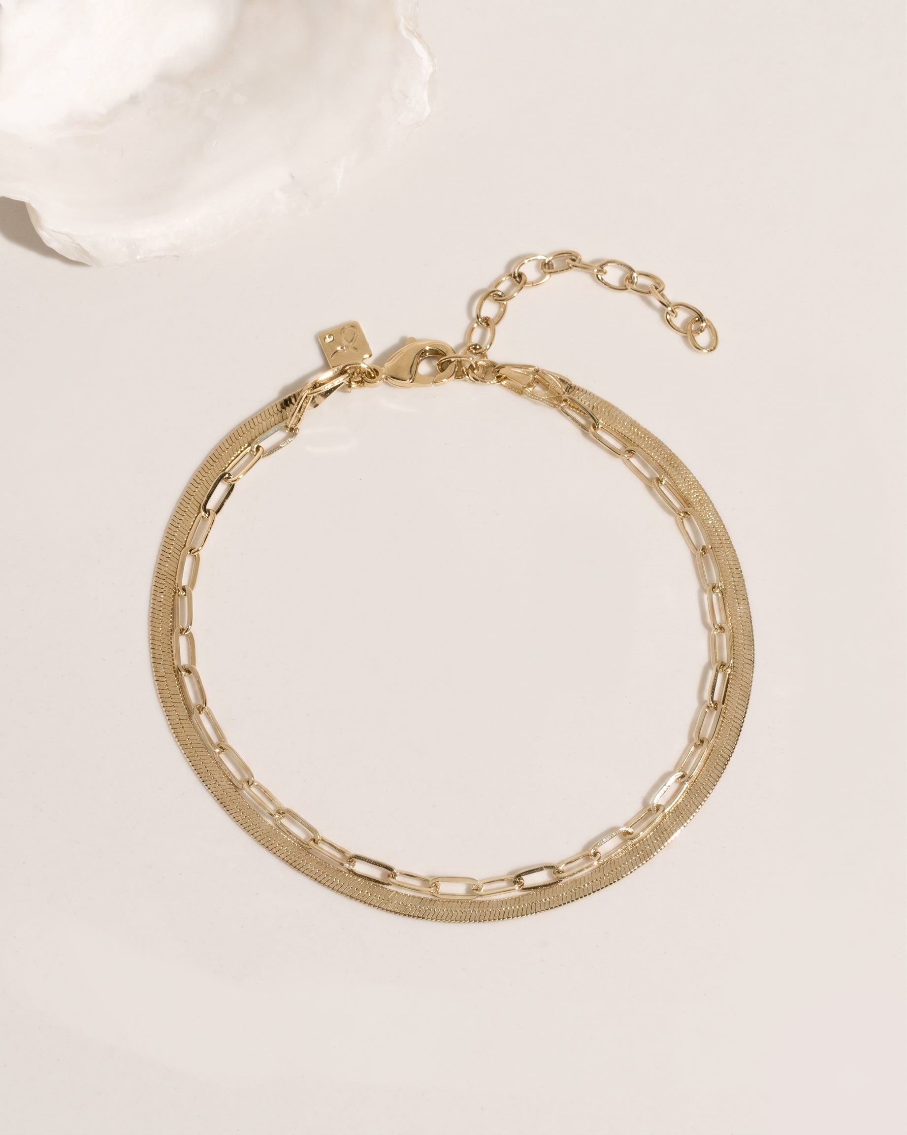 Two-layer gold anklet set combining flat herringbone chain and paperclip link chain, detail view