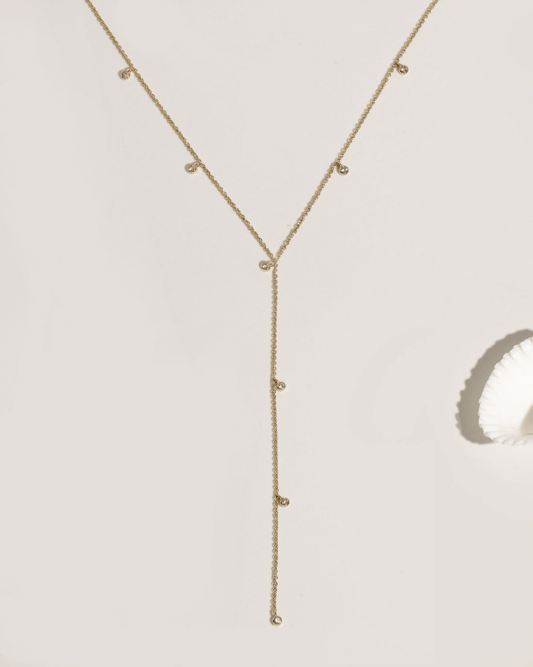 Gold lariat necklace with multiple bezel-set crystal charm drops on fine chain