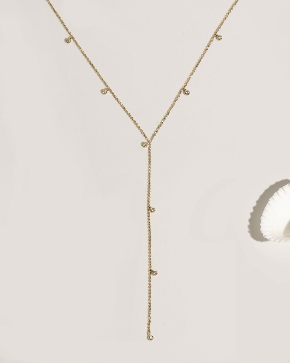 Gold lariat necklace with multiple bezel-set crystal charm drops on fine chain