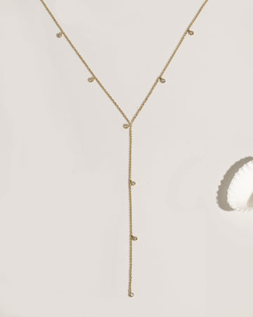 Gold lariat necklace with multiple bezel-set crystal charm drops on fine chain